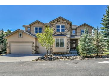 Charming two-story home with stone and stucco exterior, three-car garage, and landscaped front yard at 791 Elk Rest Rd, Evergreen, CO 80439