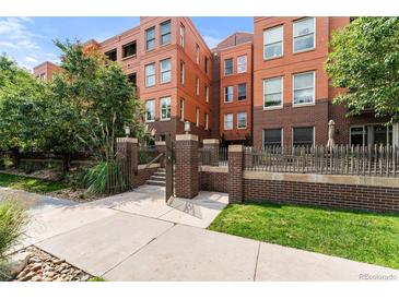 Brick exterior of a multi-story building with a landscaped walkway and fence at 1631 N Emerson St # 207, Denver, CO 80218