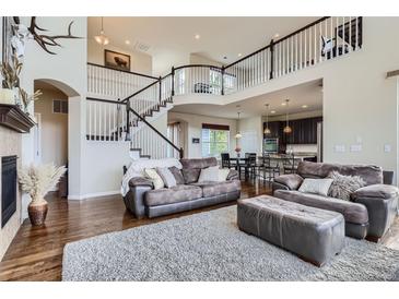 Open-concept living room with a staircase, abundant natural light, and a seamless flow to the kitchen at 7485 S Jackson Gap Way, Aurora, CO 80016