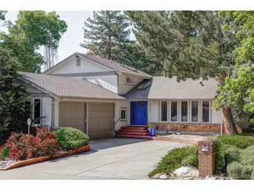 Charming home featuring a blue front door, attached two-car garage, and well-manicured landscaping with beautiful foliage at 4821 W 102Nd Ave, Westminster, CO 80031