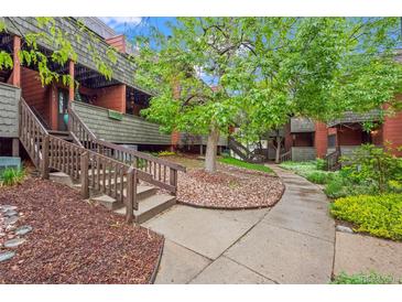Inviting walkway to building entrance with landscaped yard and mature trees on a bright day at 3050 W 32Nd Ave # 104C, Denver, CO 80211
