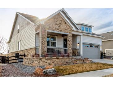 Charming home featuring stone accents, a covered porch, and a well-manicured front yard at 22773 E Narrowleaf Cir, Aurora, CO 80016
