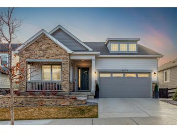 Charming home featuring a stone facade, covered porch, and well-manicured landscaping at 22773 E Narrowleaf Cir, Aurora, CO 80016