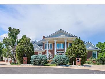 Stunning two-story brick home with white columns and manicured landscaping at 8717 Ridgepoint Dr, Castle Pines, CO 80108