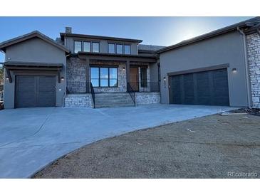 Stunning home featuring a stone facade, large windows, and a spacious three-car garage on a neatly maintained lot at 8014 Trinity Peak Ln, Castle Rock, CO 80108