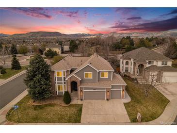 Charming two-story home featuring a well-maintained lawn, three-car garage and mountain views at sunset at 15907 W 72Nd Dr, Arvada, CO 80007