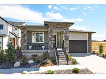 Charming home featuring stone accents, a covered porch, and a well-maintained front yard at 8360 Snake River St, Littleton, CO 80125