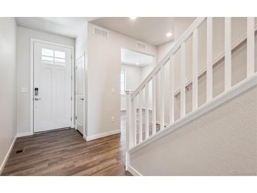 Bright entryway with a white door, wood floors, and a staircase with white railing at 3352 N Highlands Creek Pkwy, Aurora, CO 80019