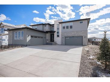 Beautiful two-story home with gray siding, stone accents, a spacious driveway, and a two-car garage at 3564 Doubletrack Ln, Castle Rock, CO 80108
