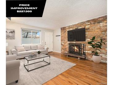 Bright living room features a fireplace, wood floors and neutral decor with a large window for ample natural light at 155 S Pennsylvania St # 308, Denver, CO 80209