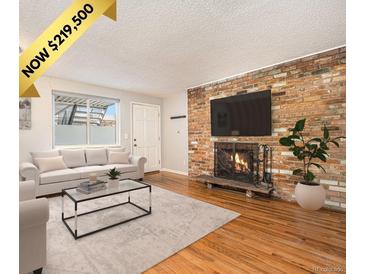 Inviting living room features a brick fireplace, hardwood floors, and a comfortable seating area with natural light at 155 S Pennsylvania St # 308, Denver, CO 80209