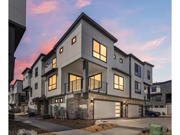 Modern townhouse boasts a two-car garage, gray exterior, stone accents, and a balcony at 2036 S Holly St # 4, Denver, CO 80222