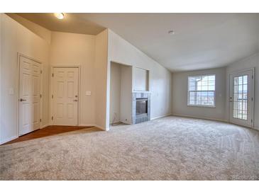 Bright living room features a fireplace, neutral carpeting, and access to the outside at 2875 Blue Sky Cir # 4-303, Erie, CO 80516
