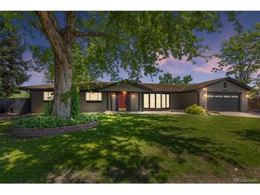 Charming home with a large tree, lush green lawn, and inviting red front door at 2180 Myrtlewood Ln, Lakewood, CO 80215