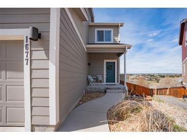 Charming home with a quaint front porch featuring seating and a welcoming blue front door with wreath at 1677 Valley Oak Ct, Castle Rock, CO 80104