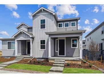 Charming gray home with well-manicured lawn, covered entry, and tidy landscaping under a bright blue sky at 14101 Deertrack Ln, Parker, CO 80134