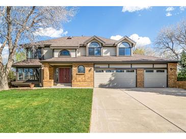 Two-story home showcasing a three-car garage, well-maintained lawn, and traditional architectural design at 20838 Parliament Ct, Parker, CO 80138