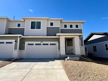 Two-story townhome with neutral siding, large windows, a two-car garage, and a well-maintained front yard at 6605 N Nepal St, Aurora, CO 80019