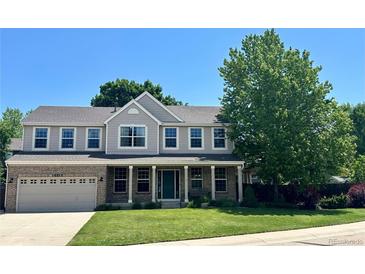 Charming two-story home features a welcoming front porch, lush lawn, and mature trees at 10512 Cimarron St, Longmont, CO 80504