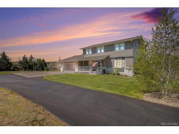 Charming two-story home with a covered front porch and well-manicured lawn under a colorful sunset sky at 6871 S Himalaya Way, Centennial, CO 80016
