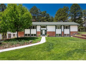 Charming ranch-style home features a lush front yard with mature trees and walkway leading to the front door at 33589 Robin Ct, Elizabeth, CO 80107