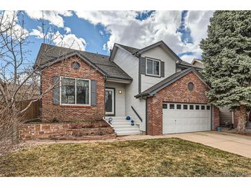 Charming two-story home featuring a brick facade, white siding, well-maintained lawn, and an attached two-car garage at 9821 Rock Dove Ln, Highlands Ranch, CO 80129