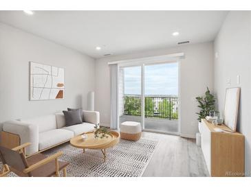 Bright living room with hardwood floors, sliding glass doors to a balcony, and modern furnishings at 485 Interlocken Blvd # 201, Broomfield, CO 80021