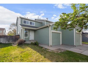 A charming two-story home with a well-maintained lawn, white door, and attached two-car garage at 747 Mockingbird St, Brighton, CO 80601