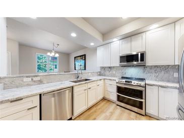 Modern kitchen featuring white cabinetry, stainless steel appliances, and granite countertops at 12919 W Burgundy Dr, Littleton, CO 80127