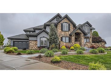 Beautiful stone front elevation featuring professional landscaping, stone accents, and a tile roof at 15102 Prairie Pl, Broomfield, CO 80023