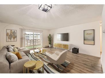 Bright living room with hardwood floors, balcony access, and neutral decor at 750 S Clinton St # 2C, Denver, CO 80247