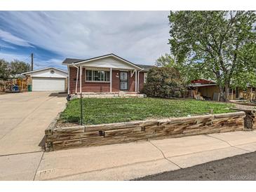 Charming brick home featuring a well-maintained lawn and a detached garage at 1325 Elder St, Denver, CO 80221