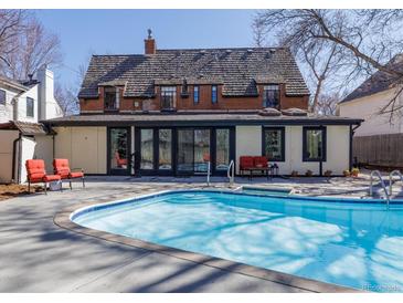 Backyard pool and outdoor living area of brick two-story home with full wall of glass doors at 629 Bellaire St, Denver, CO 80220