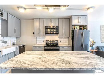 Bright kitchen features gray cabinets, subway tile backsplash, and center island with marble countertop at 1050 N Corona St # 206, Denver, CO 80218