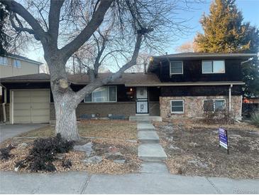 Charming two-story home with a unique facade featuring stone and brick accents, complemented by mature trees and landscaping at 2995 S Whiting Way, Denver, CO 80231