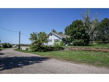 Charming single-story home with blue siding and mature trees surrounding the property at 6597 S State Highway 83, Franktown, CO 80116