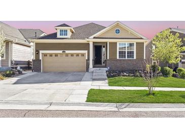 Charming single-Gathering home showcasing a landscaped front yard, attached garage and inviting entry way at 18340 W 85Th Dr, Arvada, CO 80007