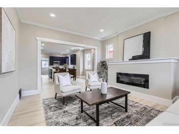 Bright living room featuring a modern fireplace, two chairs, and an open view into the kitchen at 3532 N Vine St, Denver, CO 80205