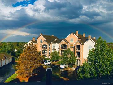 Beautiful exterior view of condo buildings with manicured landscaping and a bright rainbow overhead at 18989 E Warren Dr # G303, Aurora, CO 80013