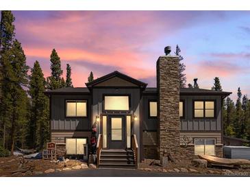 Charming gray exterior home featuring a stone chimney and inviting front porch at dusk at 400 Upper Forest Rd, Idaho Springs, CO 80452