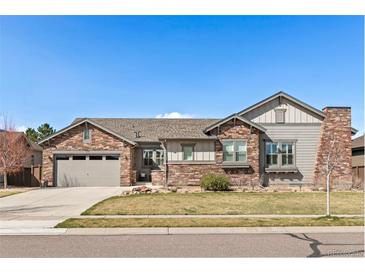 Charming single Gathering home featuring a stone facade, manicured lawn and a two-car garage, with a blue sky above at 15137 W 50Th Pl, Golden, CO 80403