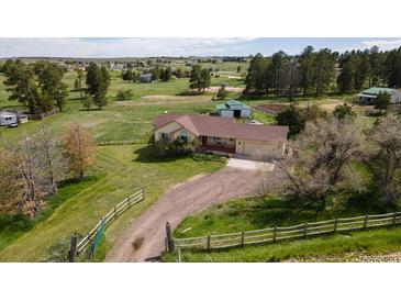 Sprawling ranch-style home with an attached garage, set on a large lot with mature trees and green pastures at 2464 Remington Rd, Elizabeth, CO 80107