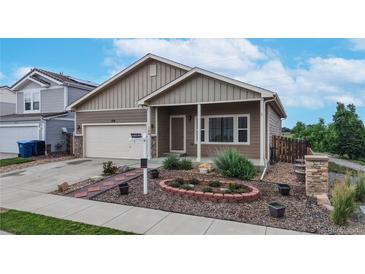 Charming home showcasing a manicured front yard and an inviting covered porch entrance with well-maintained landscaping at 169 Westin Ave, Brighton, CO 80603