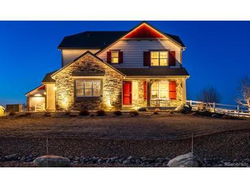 Charming two-story home featuring stone accents, red shutters, and festive lighting at dusk at 10883 E 163Rd Ct, Brighton, CO 80602