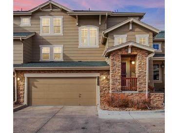 Charming townhome featuring stone accents, a spacious garage, and a welcoming covered front porch at 21993 E Jamison Pl, Aurora, CO 80016