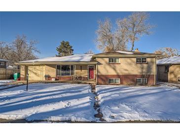 Brick ranch home with a red door and snow-covered yard at 7625 W 23Rd Pl, Lakewood, CO 80214