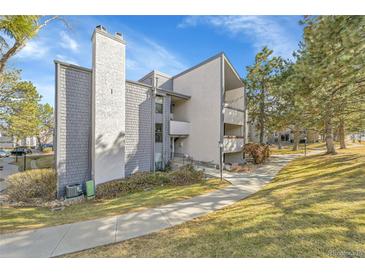 Exterior view of a multi-story condo with gray siding, a chimney, and a well-maintained lawn at 6410 S Dayton St # I1, Englewood, CO 80111