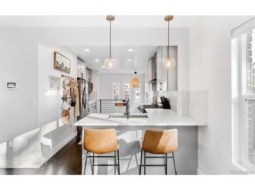 Open kitchen boasts a breakfast bar, white cabinets, and stainless steel appliances at 4270 Irving St, Denver, CO 80211