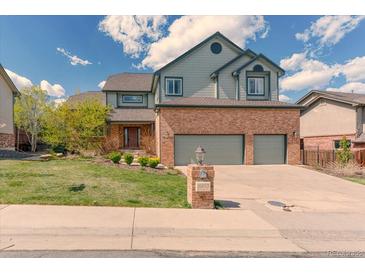 Two story home with brick facade, green siding, a three car garage and a well manicured lawn at 16652 W Archer Ave, Golden, CO 80401