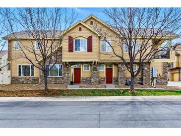 Townhouse exterior with stone accents, red doors, tan siding, and leafless trees in the front at 9980 W Jewell Ave # B, Lakewood, CO 80232